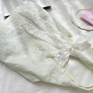 Macro view of delicate cherry blossom embroidery and white lace on a mint green tote bag