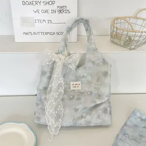 Detailed view of the ice blue floral tote bag with a large white lace bow embellishment.