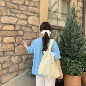 Frisse gele tote bag in Koreaanse stijl met een grote witte kanten strik op de schouder gedragen