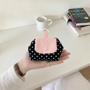 Nahaufnahme einer schwarzen Polka-Dot-Aufbewahrungstasche mit rosa Druckknopfverschluss