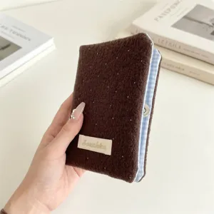Primo piano di un porta passaporto in peluche marrone a pois con bordo a quadretti blu