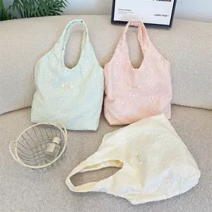 Close-up view of three pastel cherry blossom embroidered tote bags in white, pink and mint