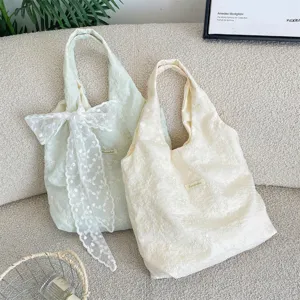 Detail view of Korean style cherry blossom embroidered tote bags in cream and light green