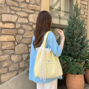 Grote gele bloemen gaas tote tas met witte kanten strik gedragen door model