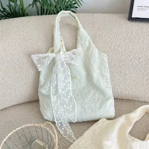 Detail of cream white tote bag with delicate cherry blossom embroidery and lace bow.