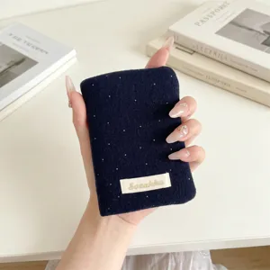 Primo piano di un porta passaporto in feltro blu scuro a pois con etichetta in tessuto.