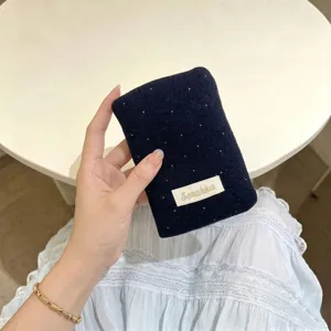 Mano che tiene un porta passaporto in feltro blu scuro a pois bianchi in una scena di vita