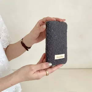 Primo piano di un porta passaporto grigio in morbido peluche a pois, tenuto con la mano
