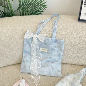 Detail view of ice blue watercolor floral tote bag with elegant white lace bow