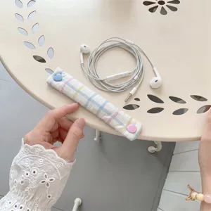 Dettaglio dell'organizzatore di cavi a quadri macaron con bottone a cuore rosa