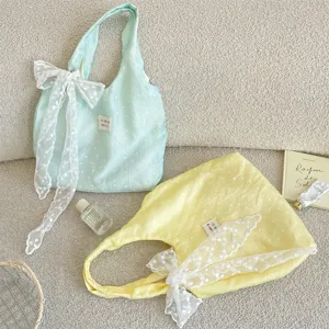 Detailopname van gele en blauwe bloemen gaze tote bags met elegante kanten strikjes