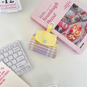 Nahaufnahme einer lila-gelb karierten Aufbewahrungstasche mit Druckknopf auf weißem Tisch.