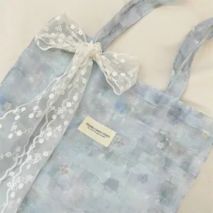 Close-up of ice blue tie-dye floral tote bag texture with elegant white lace bow detail