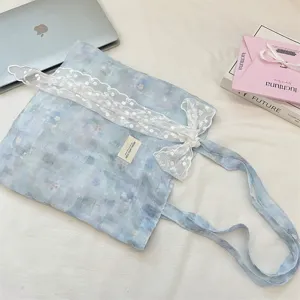 Close-up of ice blue floral tote bag with white lace bow and elegant fabric texture