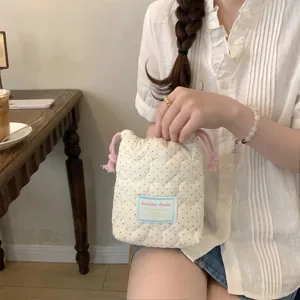 Detalle de bolsa con cordón acolchada de corazón crema con etiqueta azul claro