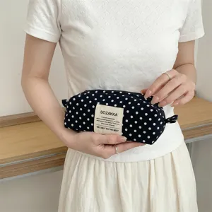 Close-up of model holding black polka dot canvas cosmetic bag with zipper detail