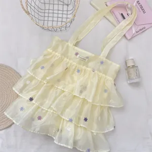 Detalle de bolsa tote de organza amarilla con capas y bordados florales suaves