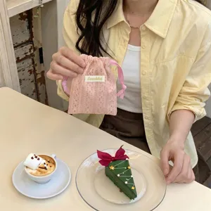 Close-up of pink lace drawstring pouch held in hand with lifestyle cafe background