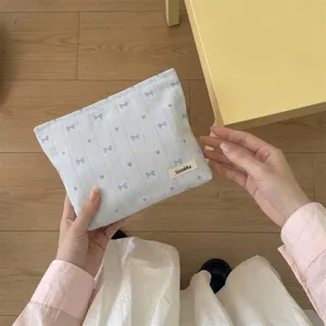 Detailed view of embroidered blue bows and hearts on light blue fabric makeup bag