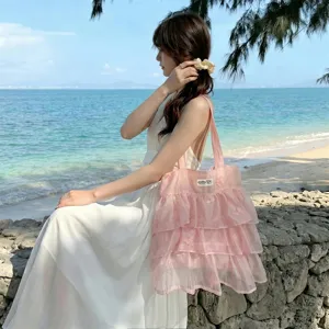 Bolso tote femenino de organza rosa con volantes y bordado de mariposas en un entorno de playa