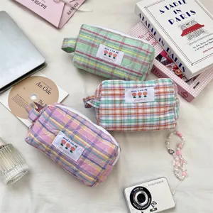 Close-up of three colorful plaid quilted pouches with flower patches on a soft background