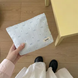 Close-up of light blue fabric makeup bag with delicate bow and heart embroidery details