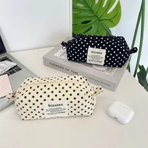 Two stylish polka dot canvas pencil cases displayed on a clean white desk with props