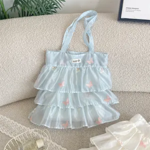 Detalle del bolso de organza azul claro con bordado de mariposas y volantes.
