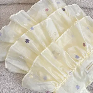 Primer plano de un bolso tote de capas de organza amarilla con bordado de flores.