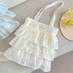 Detalle de bolsa de organza con volantes, bordado de mariposa rosa y etiqueta tejida.