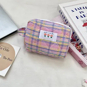 Detailed view of soft quilted pink plaid makeup bag with zipper and floral patch.