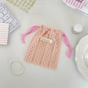 Detail view of an elegant peach lace drawstring storage bag for cosmetics and small items.