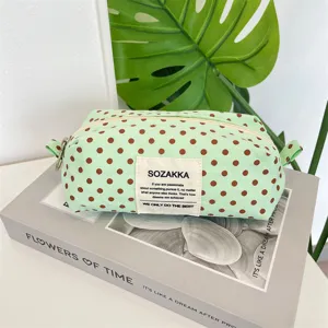 Detailed view of a mint green polka dot canvas pouch with a fabric SOZAKKA brand label.