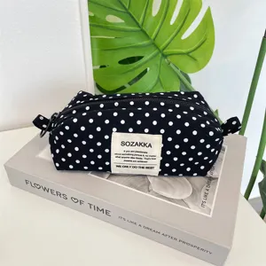 Detailed view of a black and white polka dot canvas pencil case on an aesthetic book prop