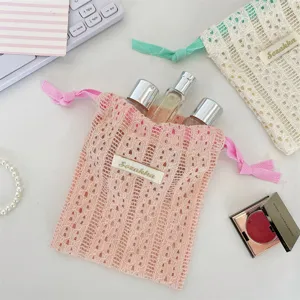 Macro view of a pink lace drawstring storage pouch containing small perfume bottles.