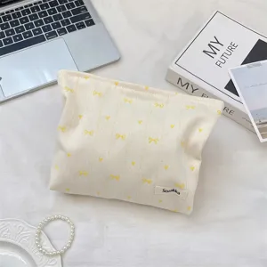 Close-up of cream canvas cosmetic bag with yellow bow embroidery and Sozakka label
