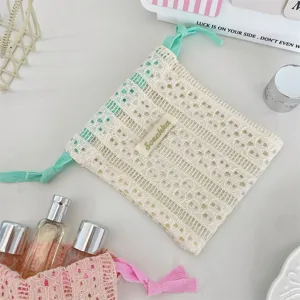 Detailed macro view of cream white hollow lace drawstring bag for cosmetic storage