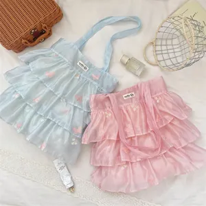Detalle de bolsos de organza con volantes en rosa y azul con bordados de mariposas