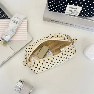Close-up detail of the cream polka dot canvas cosmetic bag showing various beauty products inside