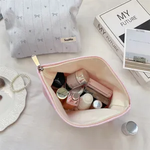 Close-up of pink embroidered makeup bag filled with skincare and cosmetic items