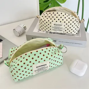Detailed view of two polka dot canvas makeup bags in cream and mint green pastel colors