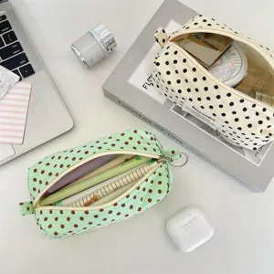Top-down view of cream and mint polka dot canvas pouches used for pens and makeup