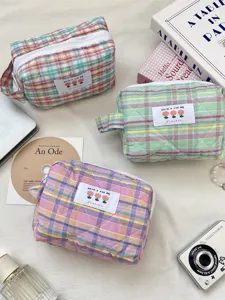 Three colorful plaid quilted cosmetic bags on a lifestyle background for daily travel use