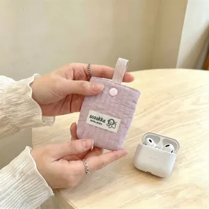 Close-up of a quilted purple earphone storage pouch held by hand on a wooden table