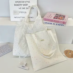 Detailweergave van crème canvas tassen met stippen en een grote elegante witte kantstrik