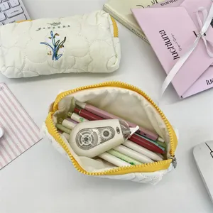 Detalle de estuche acolchado bordado abierto lleno de bolígrafos y papelería