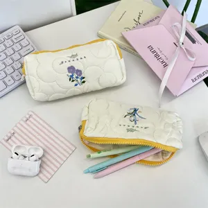 Estuche acolchado con bordado floral, detalles de almacenamiento abierto y cerrado.