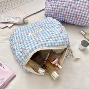 Blue gingham quilted cosmetic bag filled with various skincare and makeup products.