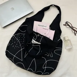 Draufsicht auf einen schwarzen Segeltuch-Shopper mit weißen abstrakten Linien.