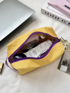 Grote gele canvas tas met paarse rits voor cosmetica of briefpapier op een bureau